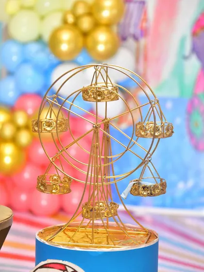 A miniature ferris wheel prop, perfect for holding cupcakes or as a decorative piece for a carnival theme.