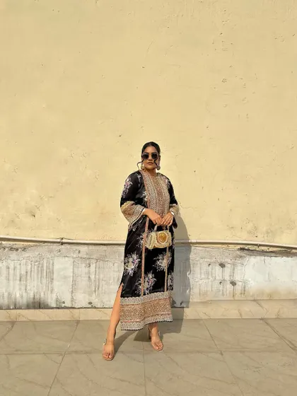 A black floral print kurta with intricate embroidery on the neckline and sleeves. Paired with a handcrafted purse, it's a look of pure desi elegance.
