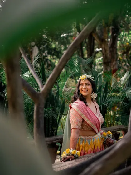 A beautiful candid of Vibhuti at her Haldi ceremony, surrounded by lush greenery. Her makeup is natural and enhances her happy glow.