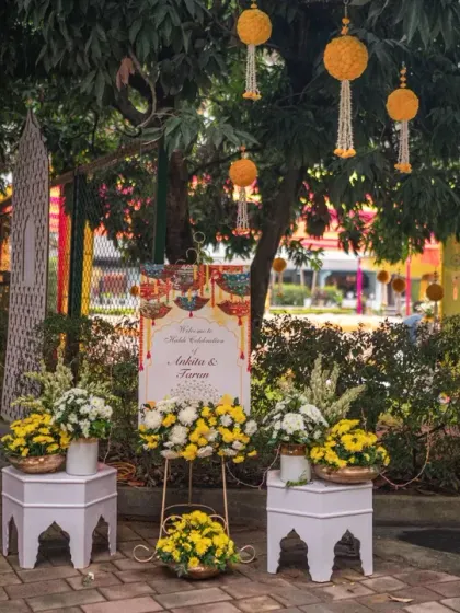 A welcome sign for a Haldi celebration, surrounded by bright yellow flowers and traditional decor elements, setting a cheerful mood.