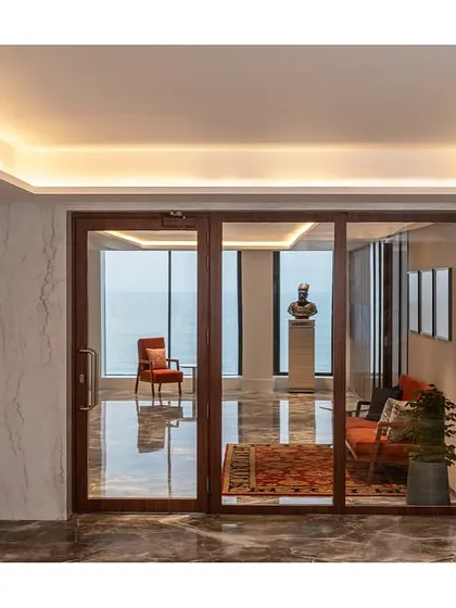 A direct view from the lift lobby through the glass entrance of The Office with a View, framing the ocean vista and establishing the project's key feature.
