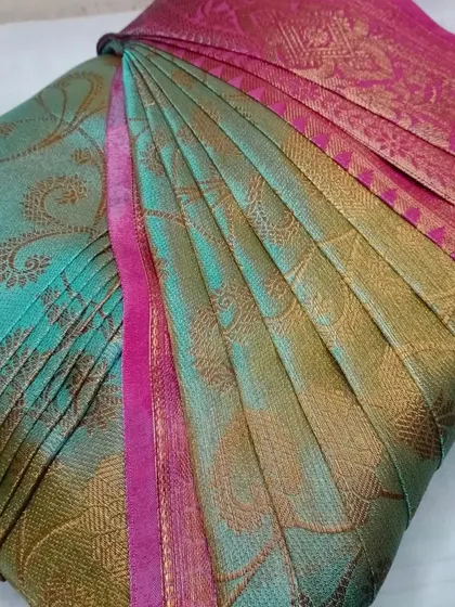 This teal and pink saree has a beautiful sheen, which is enhanced by the sharp, well-defined pleats. It's ready for a flawless drape.