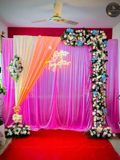 A beautiful backdrop for an anniversary or engagement. The design features a "Better Together" neon sign against vibrant pink drapes, framed by a colorful floral arch.