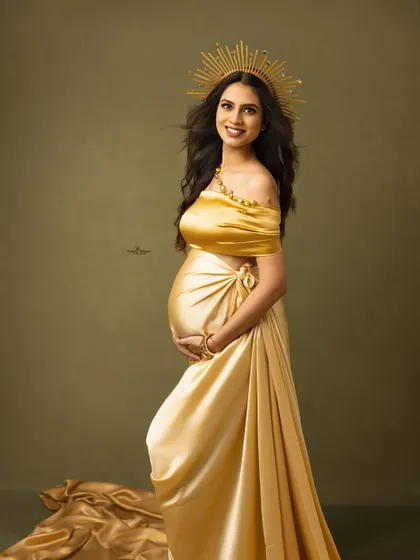 A regal portrait of a mother-to-be wearing a golden sunburst crown. This accessory adds a touch of goddess-like glamour to the maternity session.