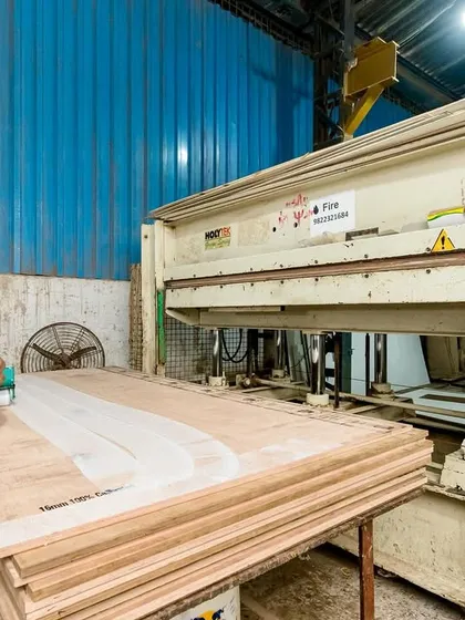 A worker operates our hydraulic press, which is used to laminate surfaces onto plywood. This ensures a bubble-free, durable finish for desktops and cabinet doors that can withstand daily office use.