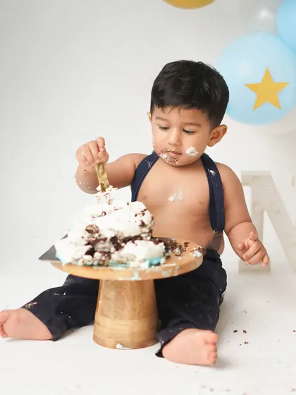 A little boy gets serious about his cake during his first birthday cake smash. The concentration on his face is priceless.