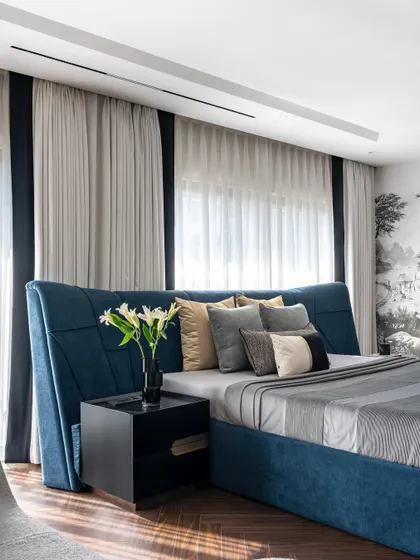 Another angle of the Evelyn master bedroom, showing the relationship between the bed, the bedside table, and the floor-to-ceiling curtains. The design is a masterclass in layering textures and creating a sophisticated mood.
