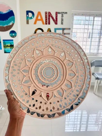 A delicate and elegant Lippan art piece in a soft peach color with intricate mirror work.