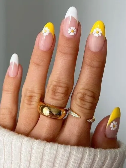 A cheerful and sunny French manicure featuring bright yellow tips on some nails and classic white on others. The look is finished with a delicate hand-painted daisy on the accent nails for a touch of floral fun.