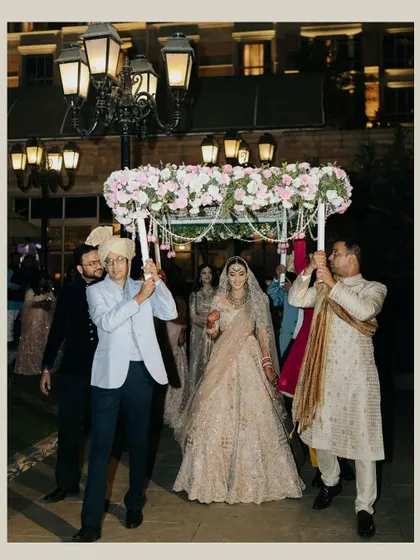 The bride's grand entrance under a beautiful floral phoolon ki chadar, a moment filled with tradition and family love.