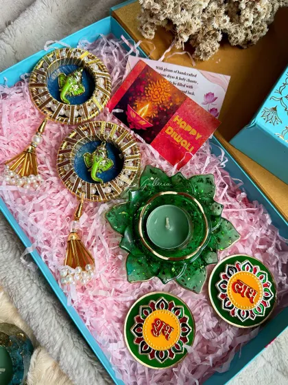 A green-themed Diwali hamper with Ganesha hangings, a lotus diya, and "Shubh Labh" coasters.