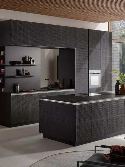 The award-winning wickerwork design shown in a black oak finish, paired with a sleek, handleless island for a modern yet timeless kitchen.