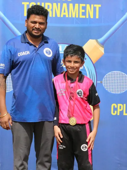 A coach proudly stands with one of his players who has won a medal in the tournament.