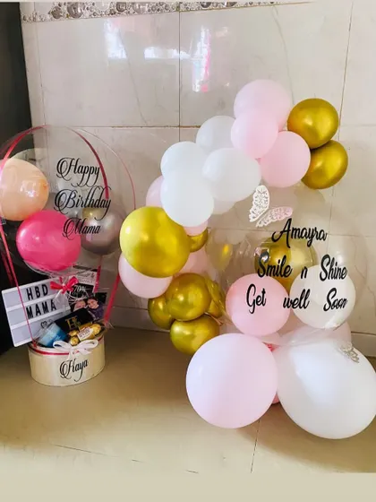This image shows two different ways to style our personalized bubble balloons. One is part of a hot air hamper, and the other is the centerpiece of a beautiful balloon garland.