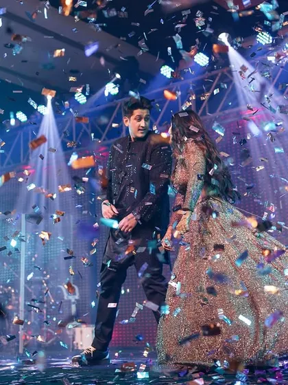 A dynamic shot of the couple mid-performance, with a shower of confetti adding to the excitement and energy of their Sangeet.