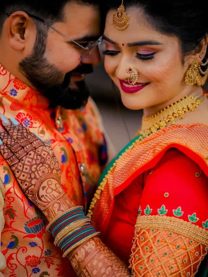 A detailed close-up of the bride's henna-adorned hand resting on the groom's arm, showcasing the intricate mehndi art and her beautiful jewelry.