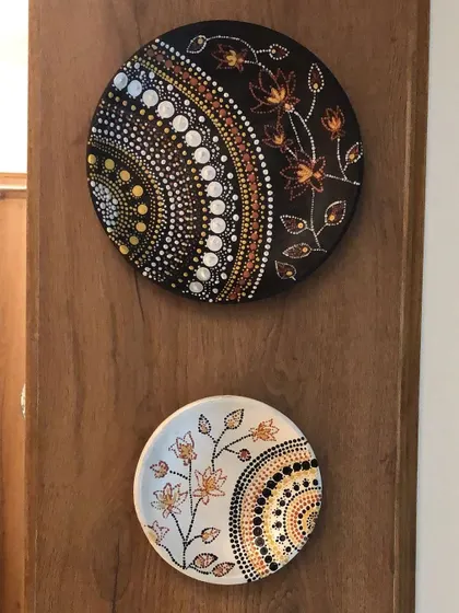 A set of two beautiful dot art plates, one with a dark background and one with a light one, hanging as wall decor.