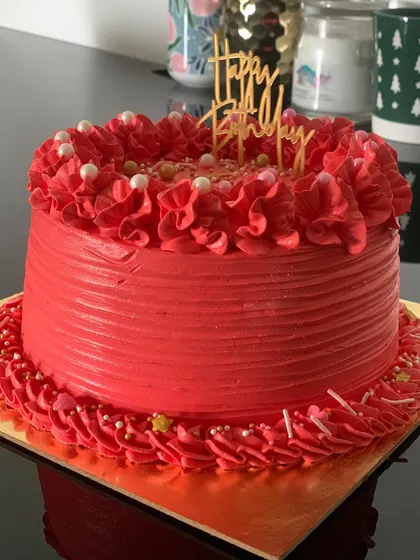 A simple yet bold red birthday cake. The textured icing and piped border give it a classic, celebratory feel.