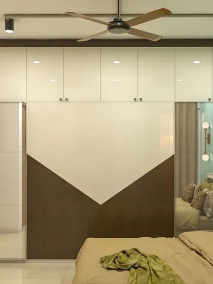 A modern bedroom with a two-tone sliding wardrobe that features a geometric design. The mirrored panel adds depth to the room, while the loft provides extra storage.