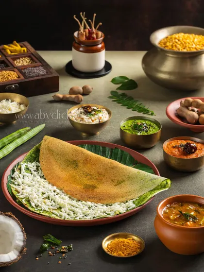 A modern presentation of a Pesarattu dosa, a green gram crepe, filled with cheese and served with various chutneys.