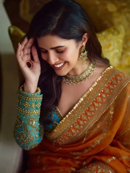 A close-up detail of the makeup and the intricate blouse sleeve. You can see the subtle henna and the flawless finish of the foundation, key elements for a polished ethnic look.