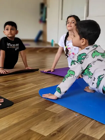 Young students practice Bhujangasana, or Cobra Pose, together. This gentle backbend is great for strengthening the spine and opening the chest.