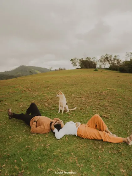 A wide shot of the couple relaxing on a grassy hill, capturing the peace and beauty of their chosen location.