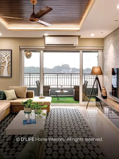 This living room features a beautiful view from the balcony, a comfortable L-shaped sofa, and a textured accent wall. The pendant lighting adds a modern, artistic touch.