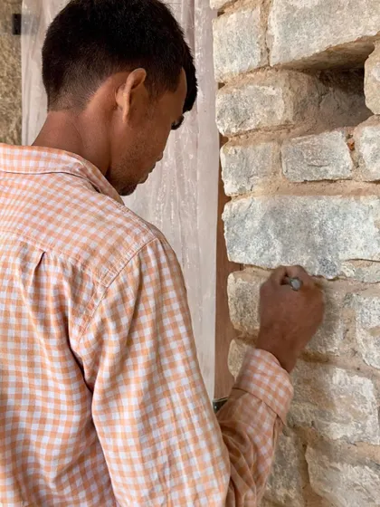 A craftsman delicately works on the stone wall, a task requiring patience and a steady hand. This close-up highlights the human touch that defines our approach to reviving traditional craftsmanship.