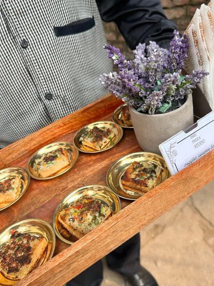 A tray of our delicious garlic cheese bread, served in individual golden dishes. This image shows our professional server presenting the appetizers, highlighting our courteous and well-groomed staff.