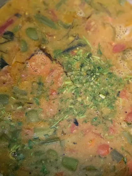 A mixed vegetable curry simmering with fresh herbs, showcasing the freshness of our ingredients.