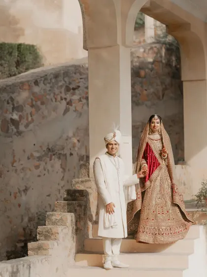 An elegant portrait of the couple on the steps of a palace, looking regal in their wedding attire.