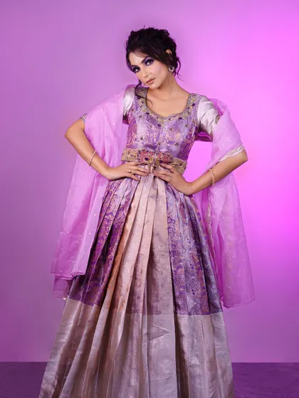 A full-length view of a lavender Langa Dhawani inspired gown, showcasing its pleated skirt and elegantly draped dupatta, perfect for a reception or formal event.