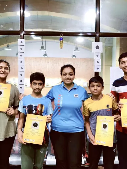 A coach poses with her group of summer campers, who are proudly holding their certificates and targets. This highlights the personal connection my coaches build with their students.