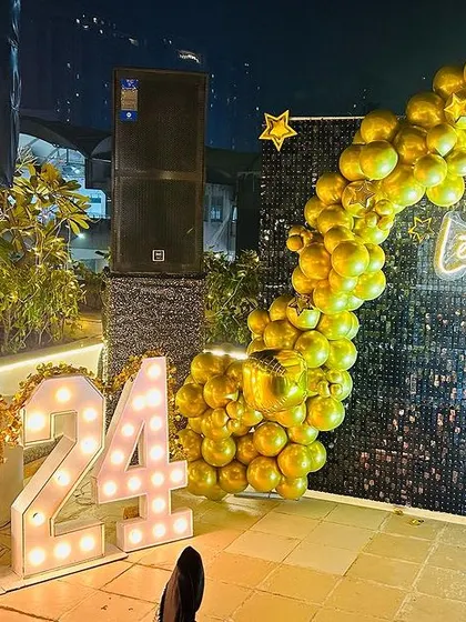 A stylish New Year 2024 party corner. This setup combines large marquee numbers with a black sequin photo wall and a contrasting gold balloon garland, creating a chic and festive spot for guests to take pictures.