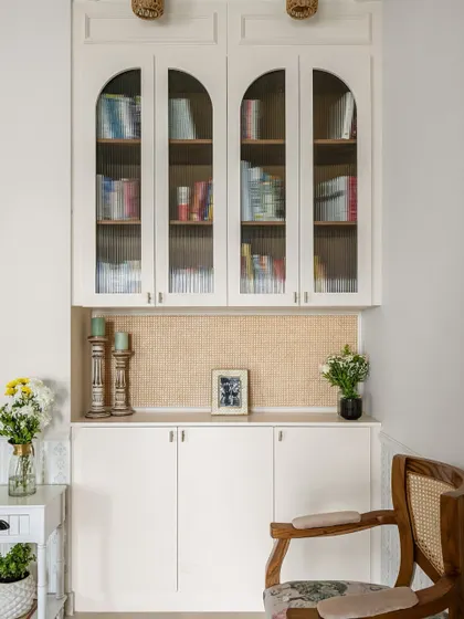 Where function meets grace. These arched cabinets with fluted glass and a warm rattan backsplash create a beautiful nook for storage and display.