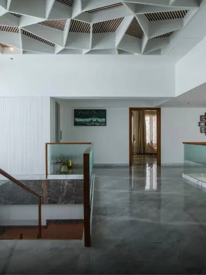 A stunning geometric coffered ceiling serves as a sculptural canopy over this hallway. The intricate design adds depth and character, turning the ceiling into a major focal point of the home.