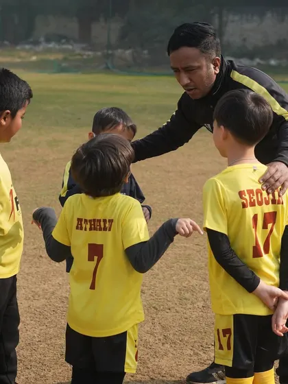 A coach giving instructions to his team. We create an environment where young talents can thrive, both on and off the field.