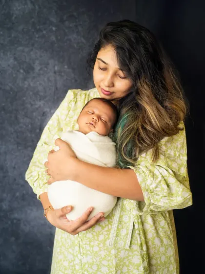 This portrait captures the serene bond between a mother and her newborn. The soft lighting and her gentle hold create a feeling of warmth and security, preserving this fleeting moment in time.
