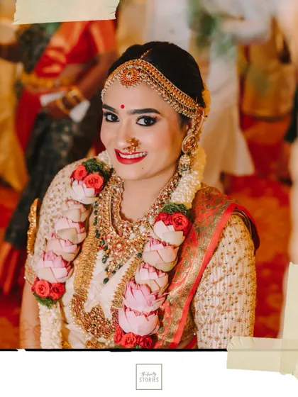 A radiant bride smiling for the camera, adorned with a beautiful lotus garland and traditional gold jewelry.