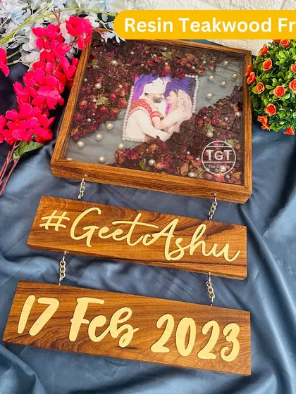 The complete view of the 12-inch resin teakwood frame with its hanging plaques. The main frame preserves the couple's varmala around their photo.