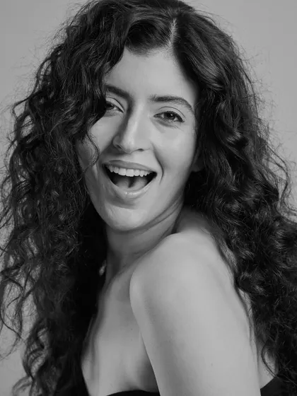 A joyful and candid moment. This black and white shot captures the life and movement of naturally curly hair, paired with a bright, happy expression.