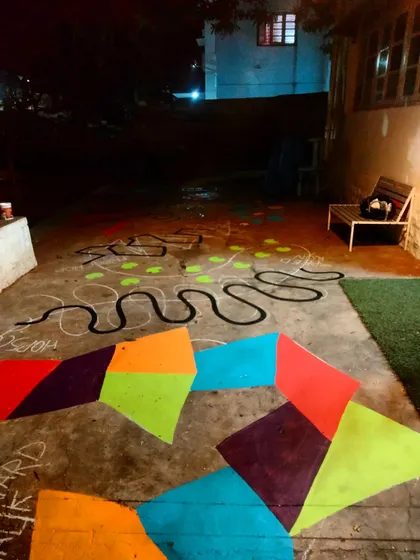 A long shot of the floor mural in progress, showing the geometric patterns and winding paths that make up the obstacle course.