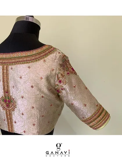 The back of an elegant ivory blouse featuring intricate embroidery in subtle, earthy tones. The design along the spine and shoulders adds a touch of understated luxury, perfect for a sophisticated look.