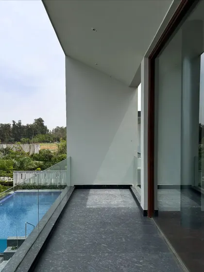This open-ended balcony at the Rosewood project provides a sweeping, uninterrupted view of the pool and garden. The simple glass railing ensures nothing obstructs the feeling of being suspended within the landscape.