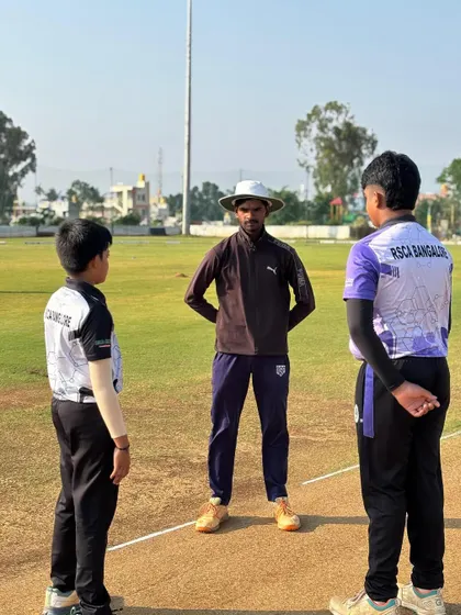 A coach stands with two young captains before the toss, a moment of mentorship before the competition begins.