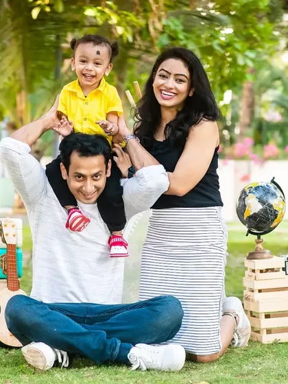 A classic family portrait from a pre-birthday outdoor shoot. The travel-themed props like the globe and suitcases add a fun, adventurous touch to the session.