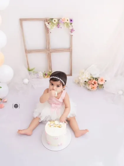 A tiny taste of sweetness. This baby girl enjoys a bite of her beautiful birthday cake in a light and airy studio setting.