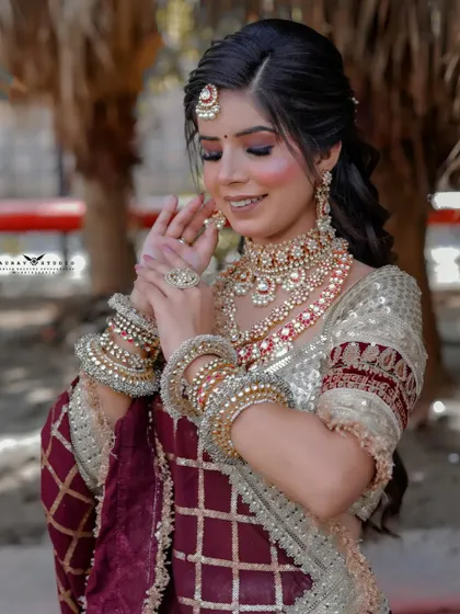 A classic pose with the bride's hands gently clasped. This shot showcases her beautiful bangles and the detailed embroidery on her blouse sleeves.