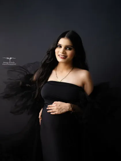 A gorgeous solo portrait of the mother-to-be. Her happy smile and the elegant black gown create a look of pure confidence and joy.